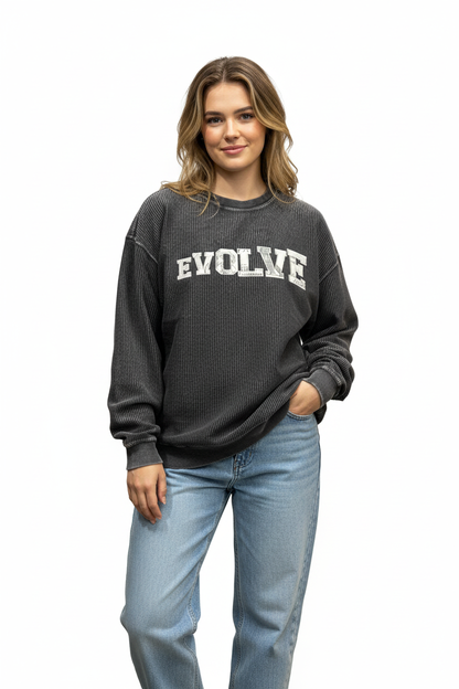 Woman wearing oversized charcoal corded sweater with EVOLVE appliqué